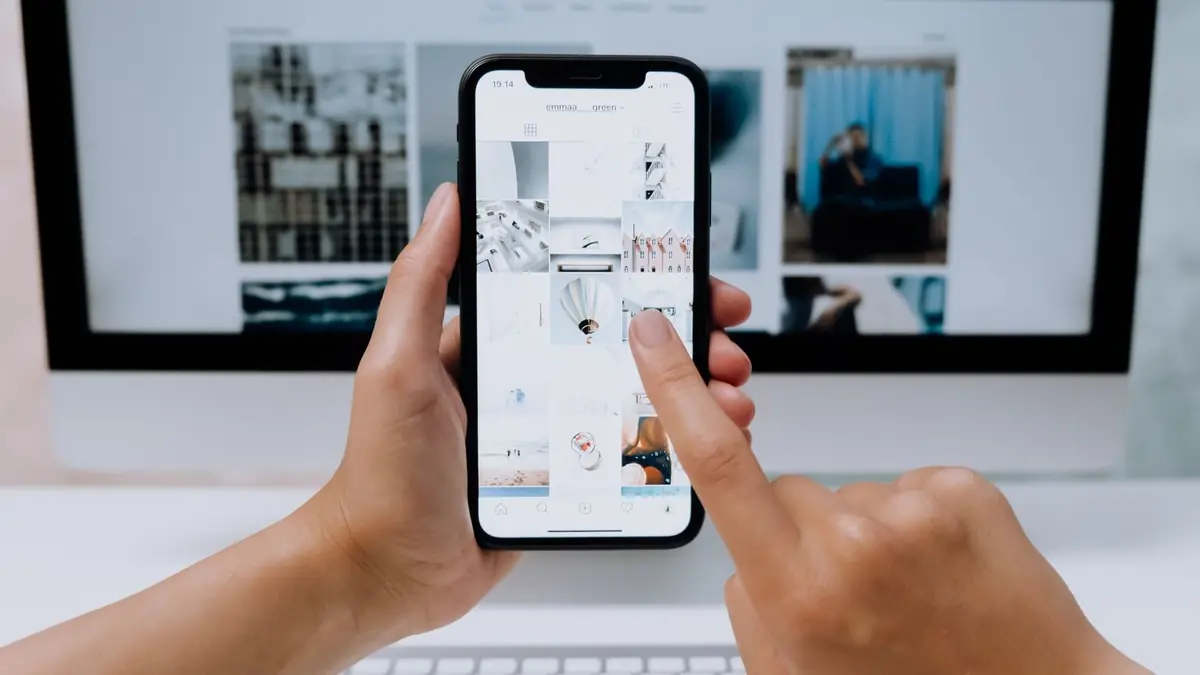 Mãos segurando smartphone com aplicativo de rede social aberto