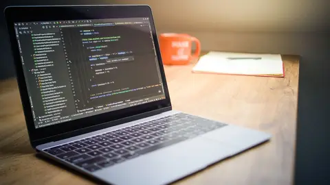 Laptop mostrando código de desenvolvimento de site profissional sobre a mesa