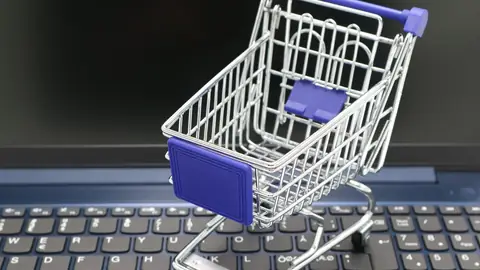 Mini carrinho de compras sobre teclado de laptop simbolizando loja virtual