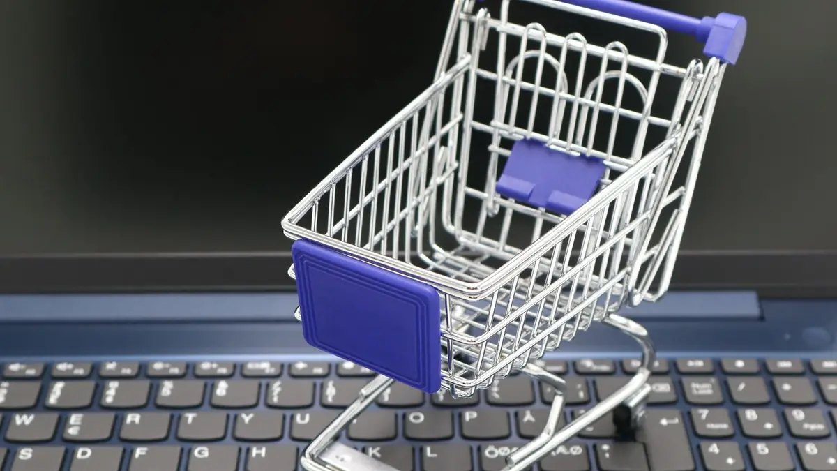 Mini carrinho de compras sobre teclado de laptop simbolizando loja virtual